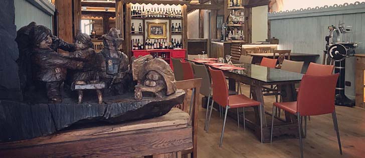 sala interna interno osteria con tavolo e bottiglie sullo sfondo