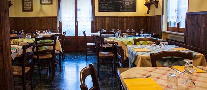 dettaglio interni tavoli apparecchiati in un locale rustico